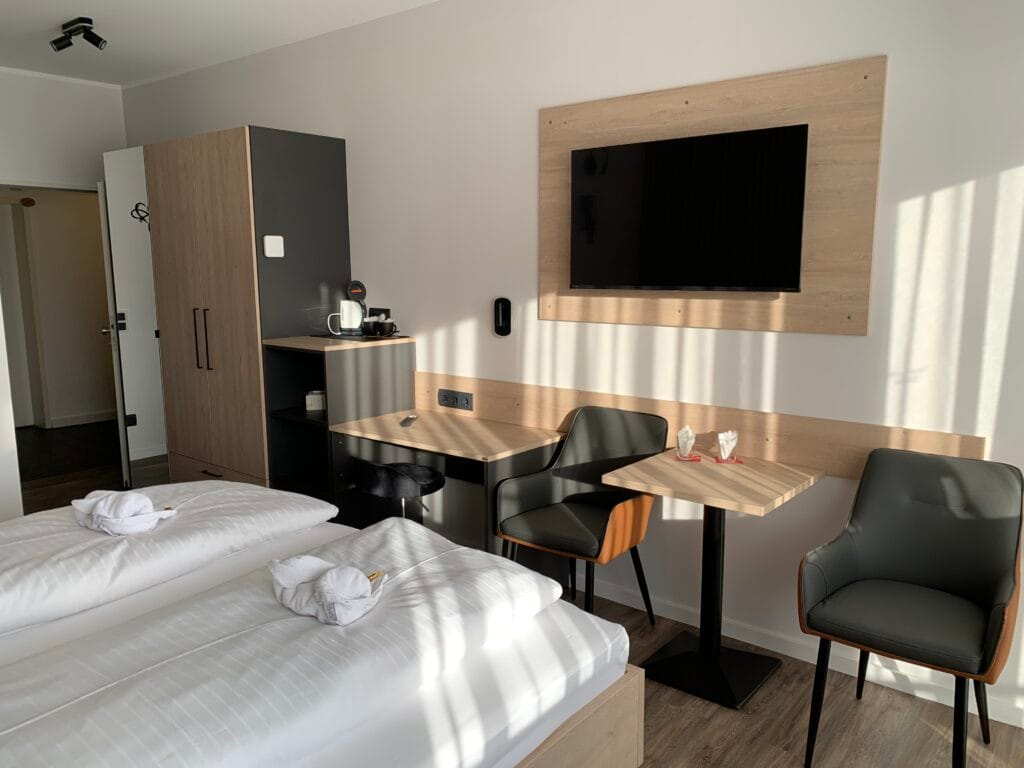 Hotelzimmer mit Schreibtisch, Sitzgruppe und Flachbild-TV an einer Holzwand