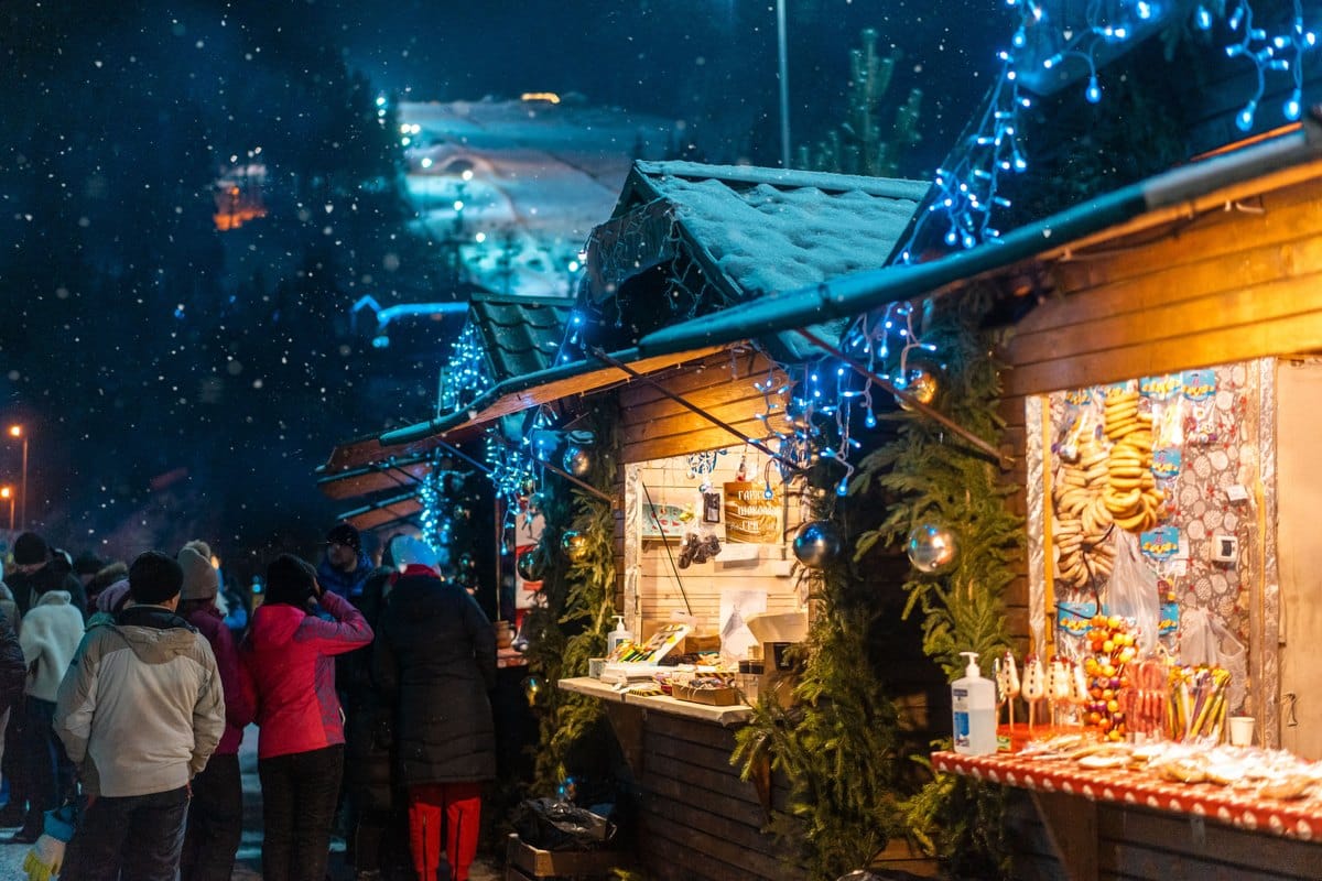 Beleuchtete Stände eines abendlichen Wintermarktes im Schnee
